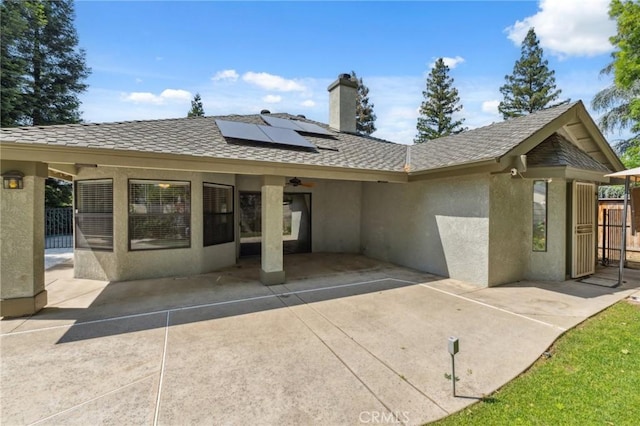 689 E Pintail Cir, Fresno, CA 93730 - back of property with fence, a patio, stucco siding, roof mounted solar panels, and a chimney