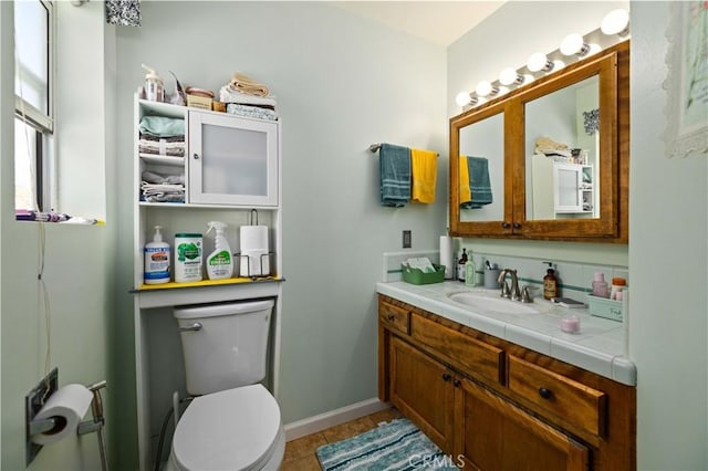 bathroom with tile patterned flooring, toilet, vanity, and baseboards