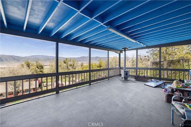 unfurnished sunroom with a wood stove and a mountain view