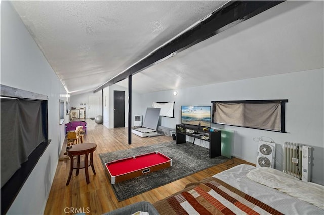 interior space featuring baseboards, vaulted ceiling with beams, wood finished floors, and a textured ceiling