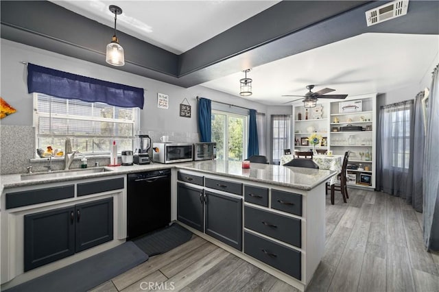 kitchen featuring light wood finished floors, visible vents, a sink, a peninsula, and appliances with stainless steel finishes