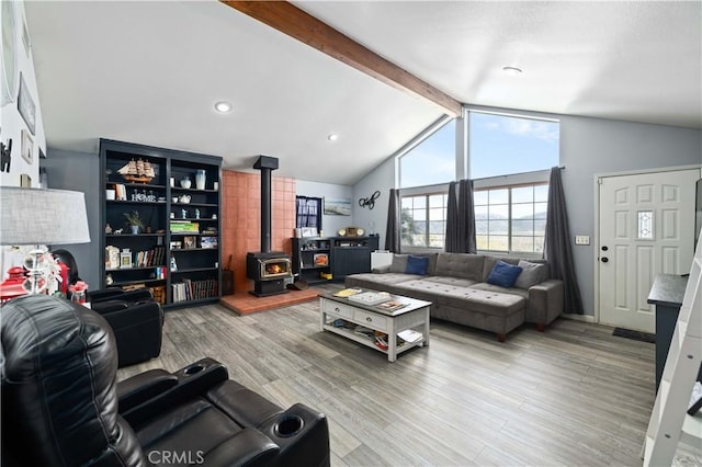 living area featuring vaulted ceiling with beams, light wood-style flooring, and a wood stove