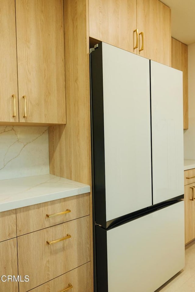 kitchen featuring freestanding refrigerator, light brown cabinetry, tasteful backsplash, and modern cabinets