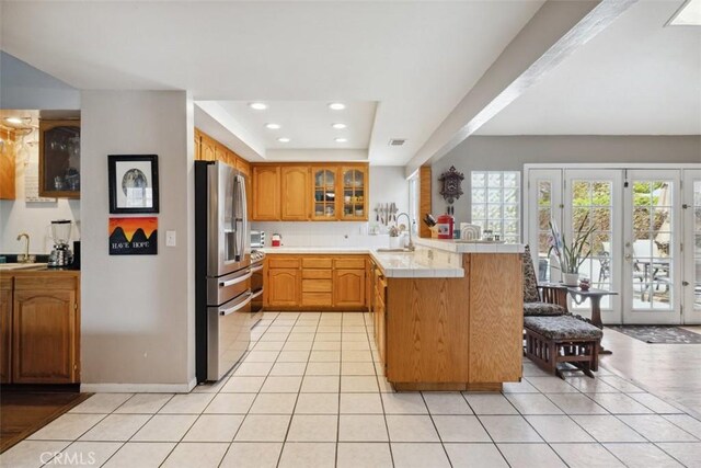 1675 Bridget Ave, Simi Valley, CA 93065 - kitchen featuring a peninsula, stainless steel fridge, glass insert cabinets, light tile patterned floors, and recessed lighting