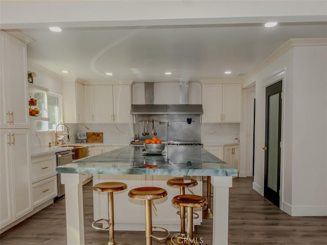 kitchen featuring a breakfast bar, dishwasher, wall chimney exhaust hood, decorative backsplash, and white cabinetry