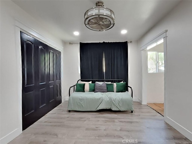 bedroom with recessed lighting, baseboards, wood finished floors, and a closet