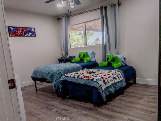 bedroom with wood finished floors, baseboards, and ceiling fan