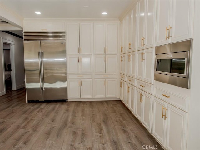 kitchen featuring built in appliances, white cabinets, light wood finished floors, and recessed lighting