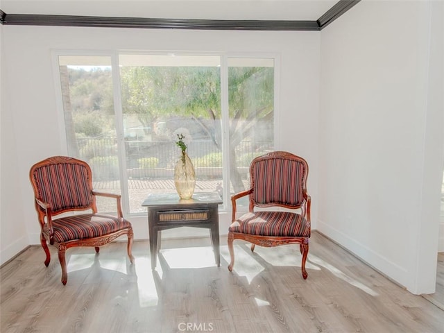 sitting room with baseboards, wood finished floors, and crown molding