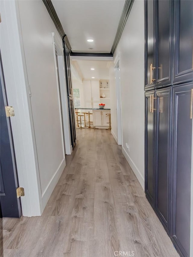 hallway with light wood finished floors, baseboards, and crown molding