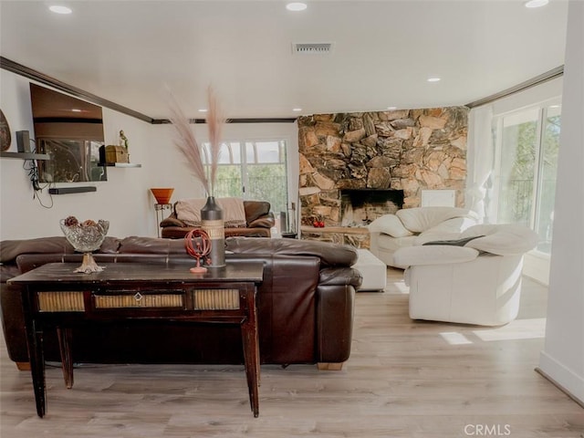 living room featuring wood finished floors, visible vents, and a stone fireplace