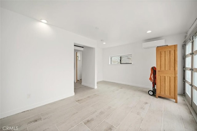 spare room featuring a healthy amount of sunlight, an AC wall unit, recessed lighting, and light wood-style flooring
