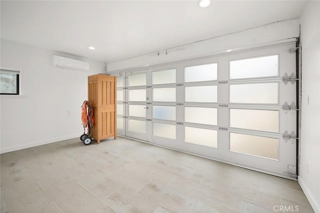 interior space with recessed lighting, a wall mounted air conditioner, and baseboards