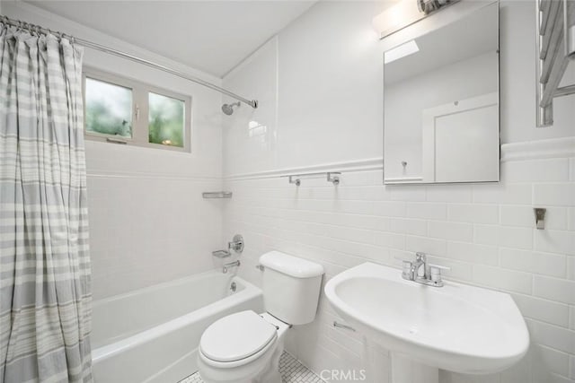 bathroom featuring a sink, tile walls, toilet, and shower / tub combo