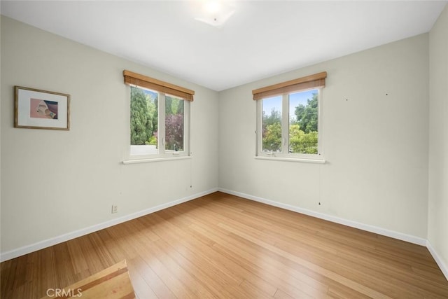 spare room featuring baseboards and light wood-style flooring