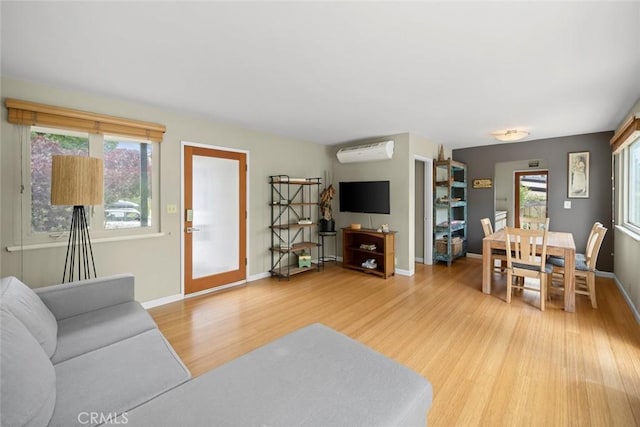 living area with wood finished floors, baseboards, and a wall mounted AC