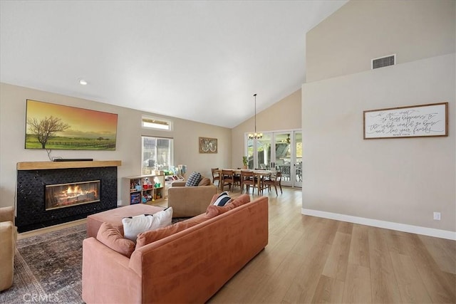 living room featuring visible vents, baseboards, a premium fireplace, wood finished floors, and high vaulted ceiling