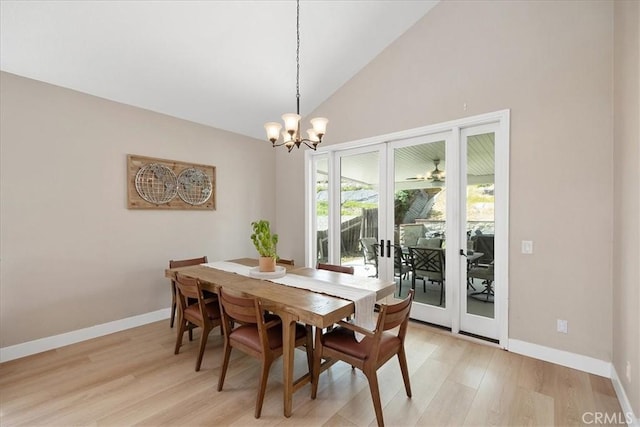 dining area with high vaulted ceiling, light wood-style flooring, baseboards, and an inviting chandelier