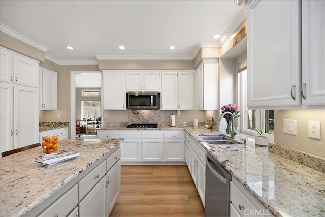 kitchen featuring stainless steel appliances, a sink, light wood-type flooring, recessed lighting, and white cabinetry
