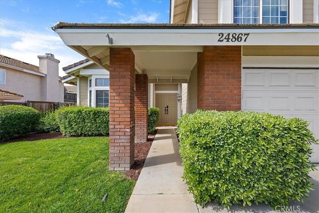 view of exterior entry with a lawn and brick siding