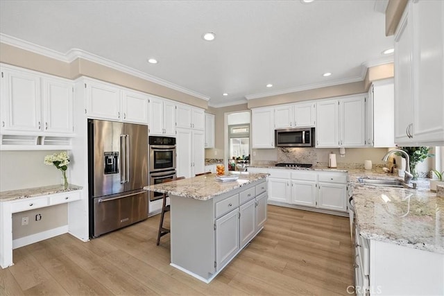 kitchen featuring light wood-style floors, appliances with stainless steel finishes, a center island, and a sink