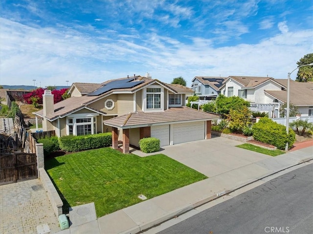 traditional-style house featuring a tiled roof, solar panels, concrete driveway, an attached garage, and a front yard
