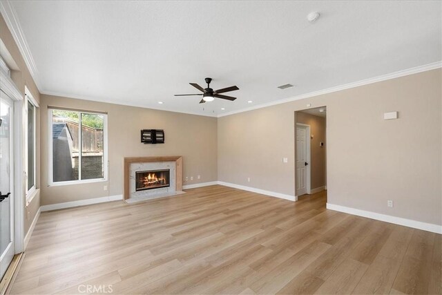 unfurnished living room with a high end fireplace, light wood-type flooring, a ceiling fan, and baseboards