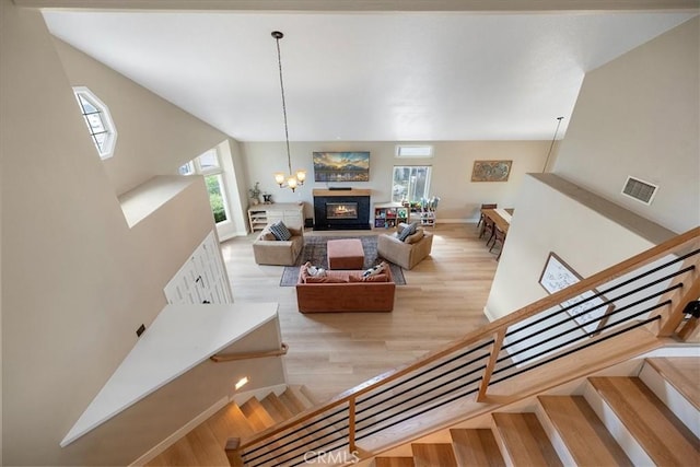 staircase with a glass covered fireplace, plenty of natural light, visible vents, and wood finished floors