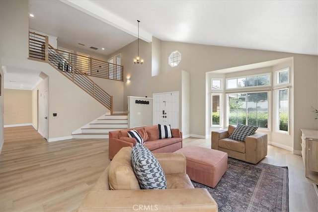 living room featuring light wood-style flooring, baseboards, an inviting chandelier, stairway, and high vaulted ceiling