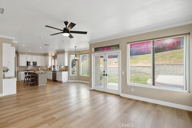 unfurnished living room featuring french doors, baseboards, a wealth of natural light, and ornamental molding