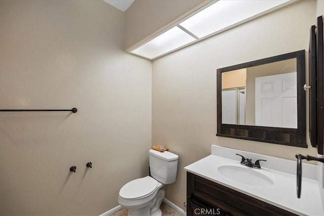 bathroom with baseboards, toilet, and vanity
