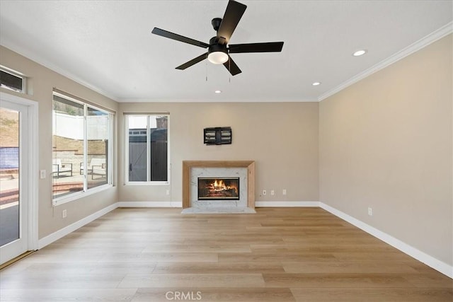 unfurnished living room with baseboards, recessed lighting, light wood-style floors, a high end fireplace, and ornamental molding