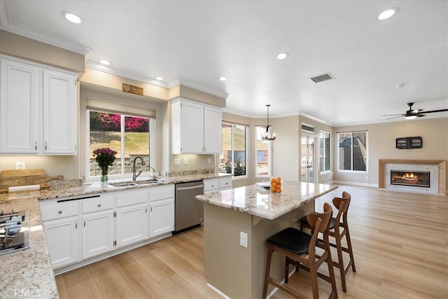 kitchen featuring stainless steel appliances, a sink, light wood-type flooring, visible vents, and ornamental molding