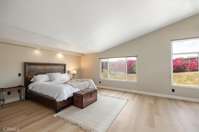bedroom with lofted ceiling, baseboards, and light wood-style floors