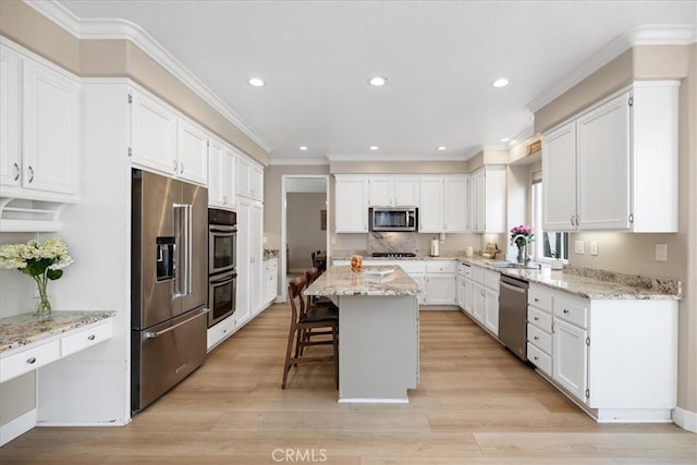 kitchen with white cabinets, recessed lighting, stainless steel appliances, ornamental molding, and a kitchen island