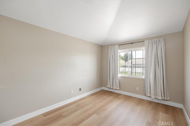 spare room with baseboards and light wood-type flooring