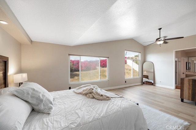 bedroom featuring lofted ceiling, baseboards, light wood-style floors, and ceiling fan