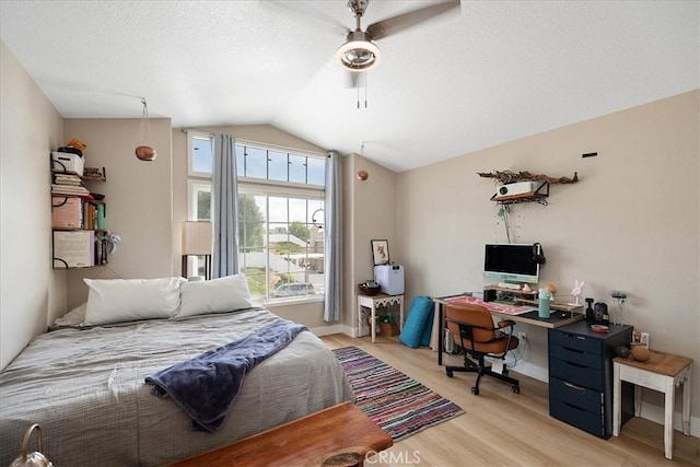 bedroom featuring light wood-style flooring, a textured ceiling, vaulted ceiling, and a ceiling fan
