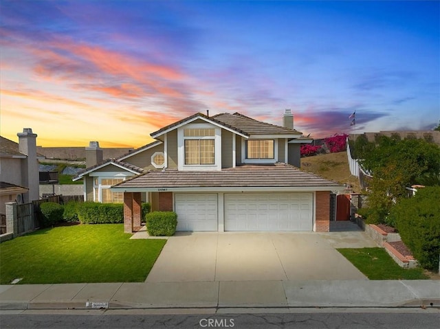 traditional-style home with a tile roof, a lawn, an attached garage, fence, and brick siding