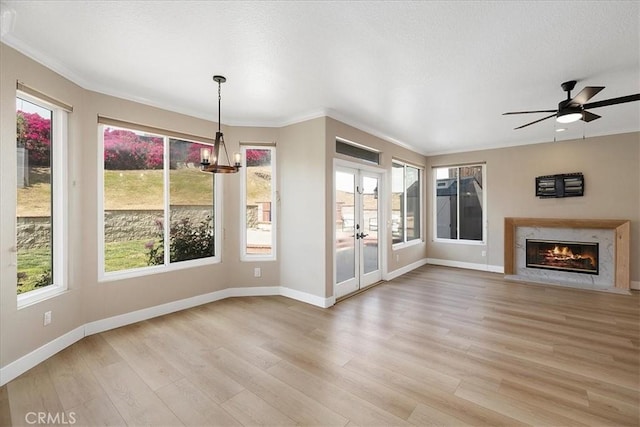 interior space with baseboards, ornamental molding, french doors, and light wood-style flooring