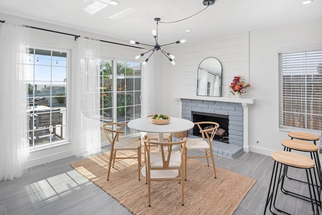 6770 Amberly St, San Diego, CA 92120 - dining space with a brick fireplace, a chandelier, wood tiled floors, baseboards, and recessed lighting