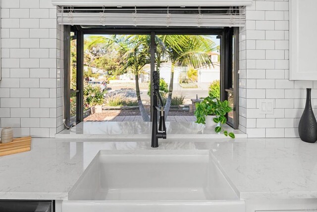 6770 Amberly St, San Diego, CA 92120 - kitchen view of decorative backsplash, light stone counters, a sink, and white cabinetry