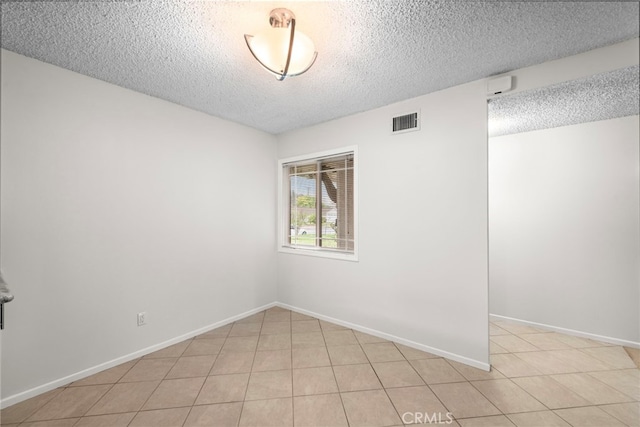 spare room featuring visible vents, a textured ceiling, baseboards, and light tile patterned flooring