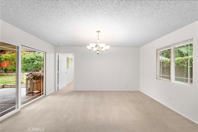 unfurnished room featuring a textured ceiling, light carpet, a chandelier, and a wealth of natural light