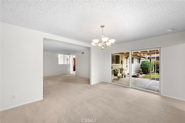 unfurnished room featuring carpet flooring, a textured ceiling, and a chandelier
