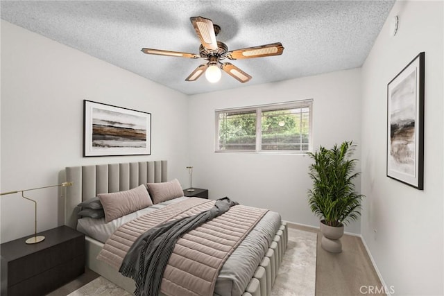 bedroom with baseboards, a ceiling fan, and a textured ceiling