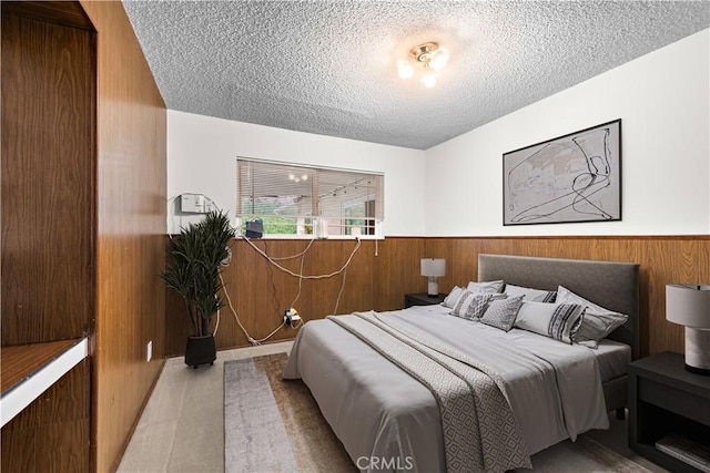 bedroom featuring a textured ceiling, a wainscoted wall, and wooden walls