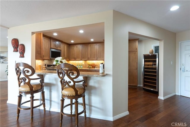 2270 Stanley Ave Unit 2B, Signal Hill, CA 90755 - kitchen featuring wine cooler, dark wood-type flooring, stainless steel microwave, tasteful backsplash, and a kitchen breakfast bar
