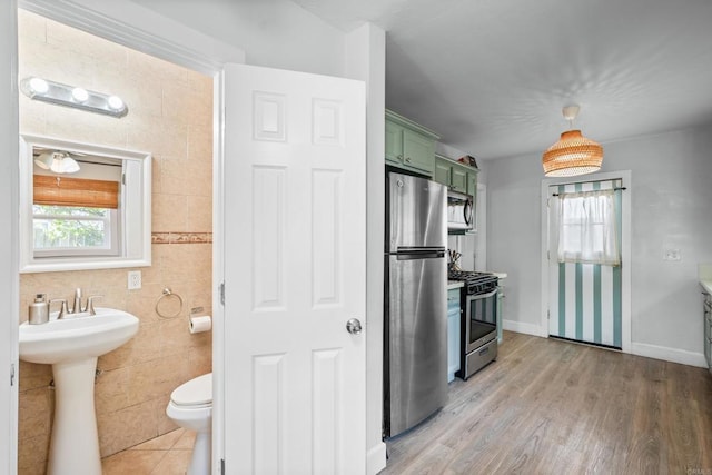 376163 Swift Ave, San Diego, CA 92104 - kitchen with green cabinets, appliances with stainless steel finishes, tile walls, light wood-style floors, and baseboards