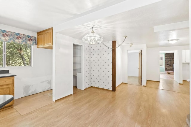unfurnished bedroom with two closets, a notable chandelier, and light wood-type flooring